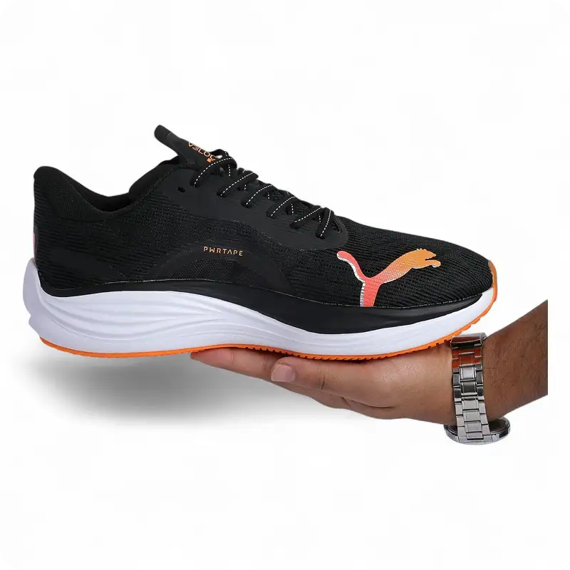 Black Puma running shoe with orange accents held in one hand