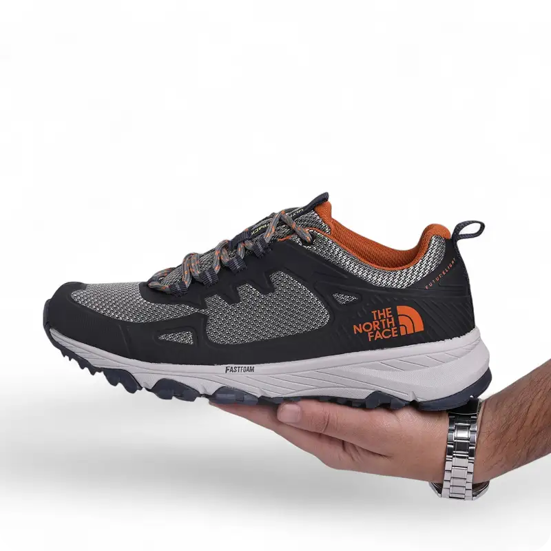 Black and gray The North Face trail shoe held in one hand